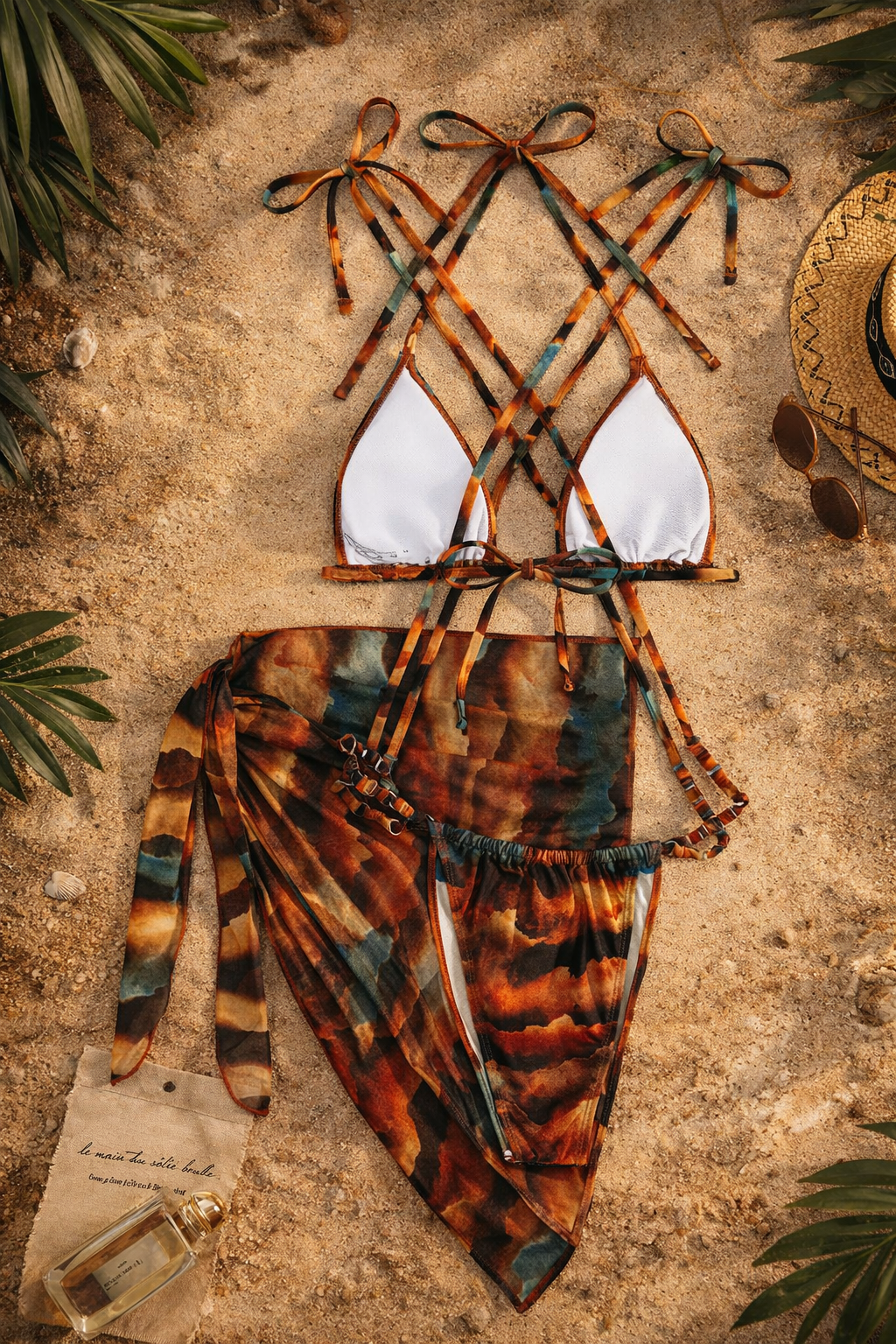 Tie-dye bikini set on a textured surface with leaves and a hat in the background